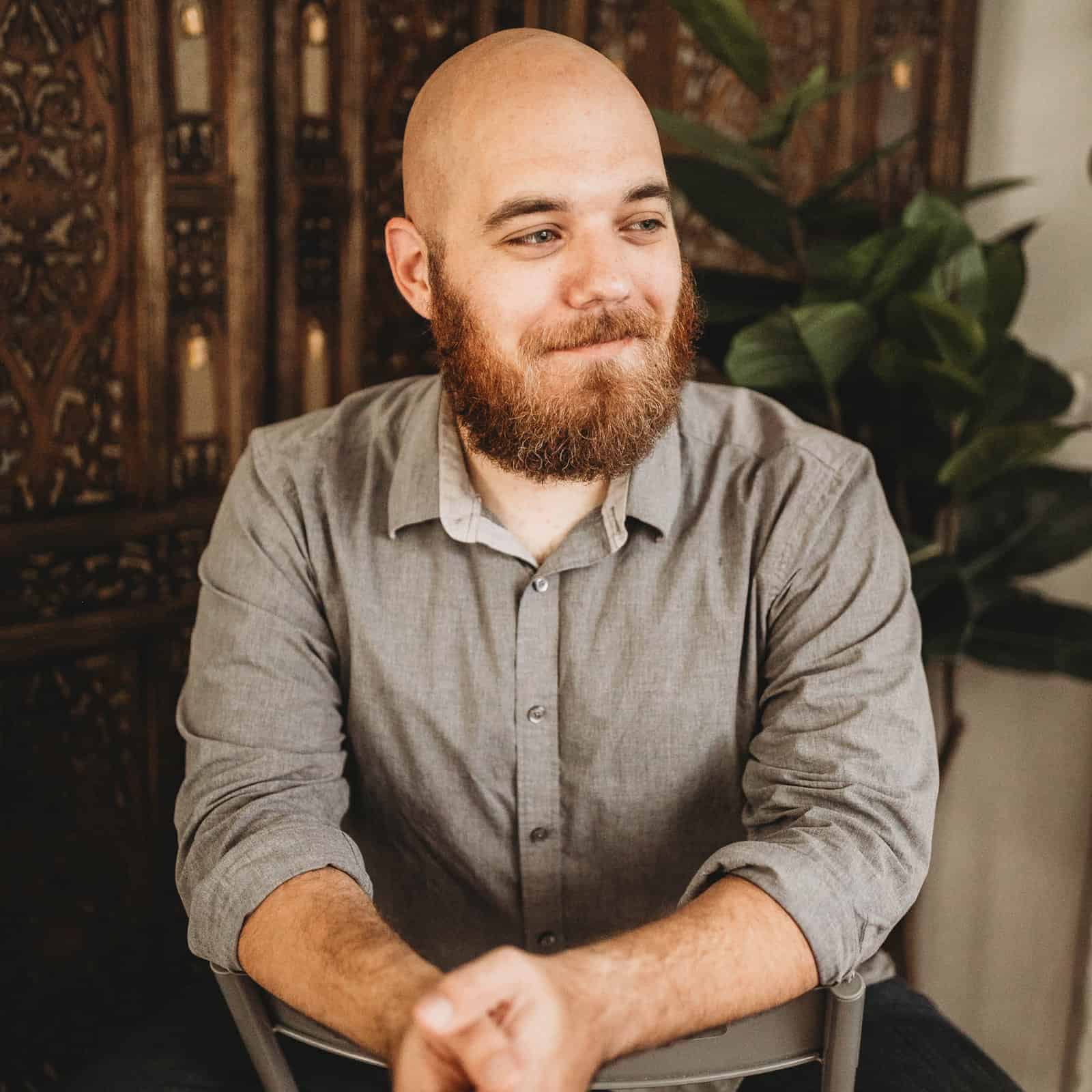 Portrait of a bearded man with a thoughtful expression in a cozy indoor environment.