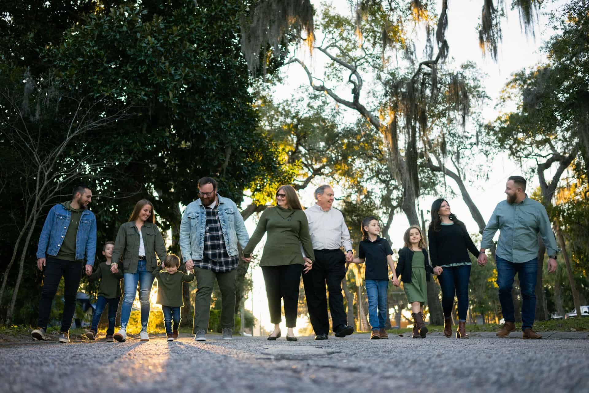 Family walking together in a park with trees and sunlight in the background.