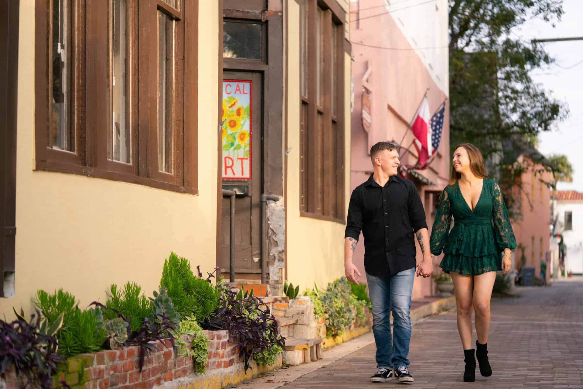 Young couple holding hands walking along a colorful city street.