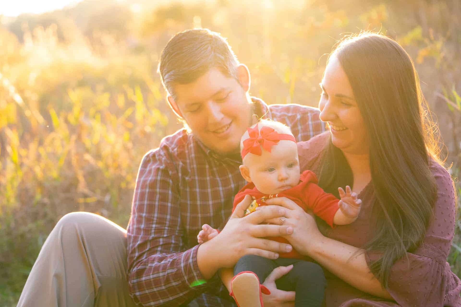 Family with baby sitting outdoors during sunset at Camp Milton.