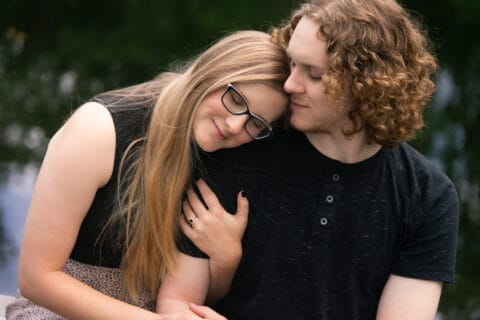 Man and woman lean on each other in front of a pond