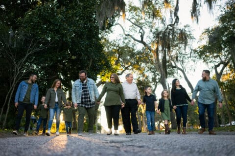 Family with several members walk on a road with greenery in the background