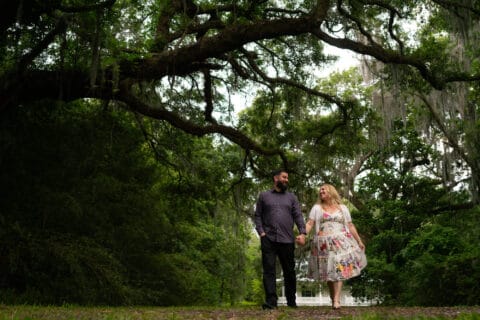 Man and woman walk holding hands through a park