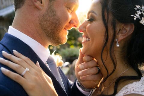 Bride and groom lean in to kiss during sunset