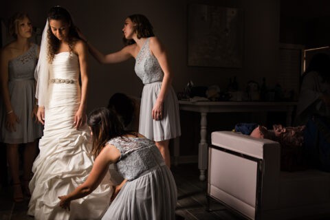 Bridesmaids help bride with her wedding dress
