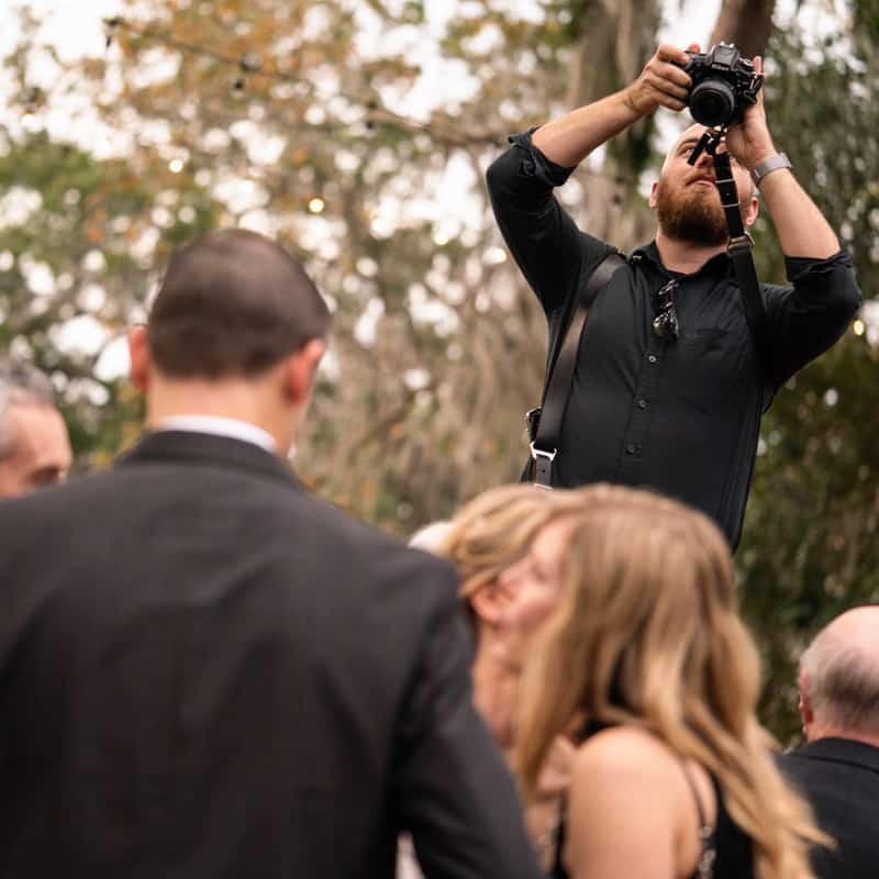 Wedding photographer standing over people taking a photo of them