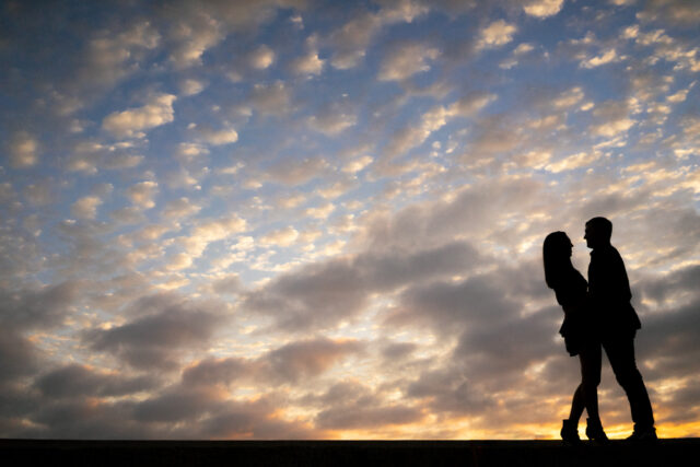 Silhouette of man and woman with the sunrise and clouds in the background