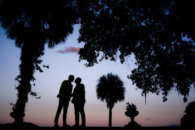 Silhouette of grooms leaning into kiss with sunset in the background