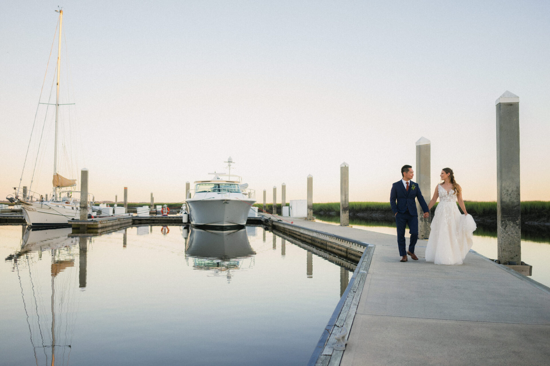 married couple walks on the dock at oyster bay yacht club by wedding photographer Chris David