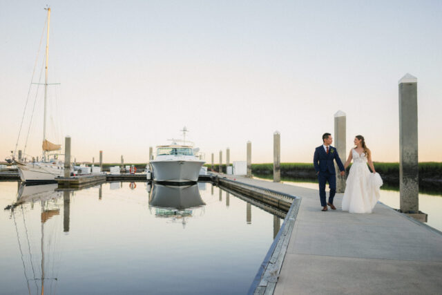 married couple walks on the dock at oyster bay yacht club by wedding photographer Chris David