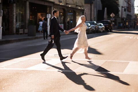 Bride and groom cross a crosswalk while holding hands
