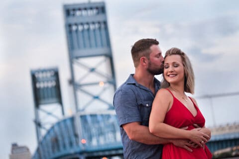 Man and woman hold each other in front of Main Street Bridge in downtown Jacksonville, FL