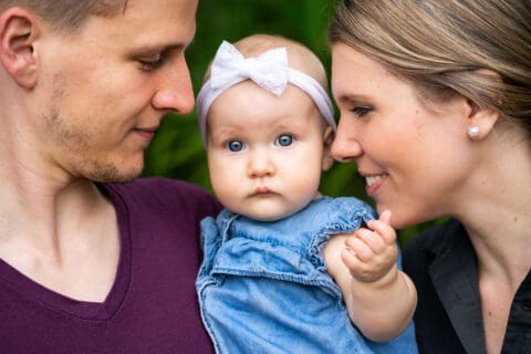 Man and woman smile at a baby who is looking at the camera